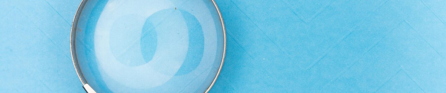 Close-up of a magnifying glass on a blue surface, ideal for search and exploration themes.