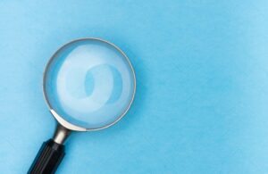 Close-up of a magnifying glass on a blue surface, ideal for search and exploration themes.